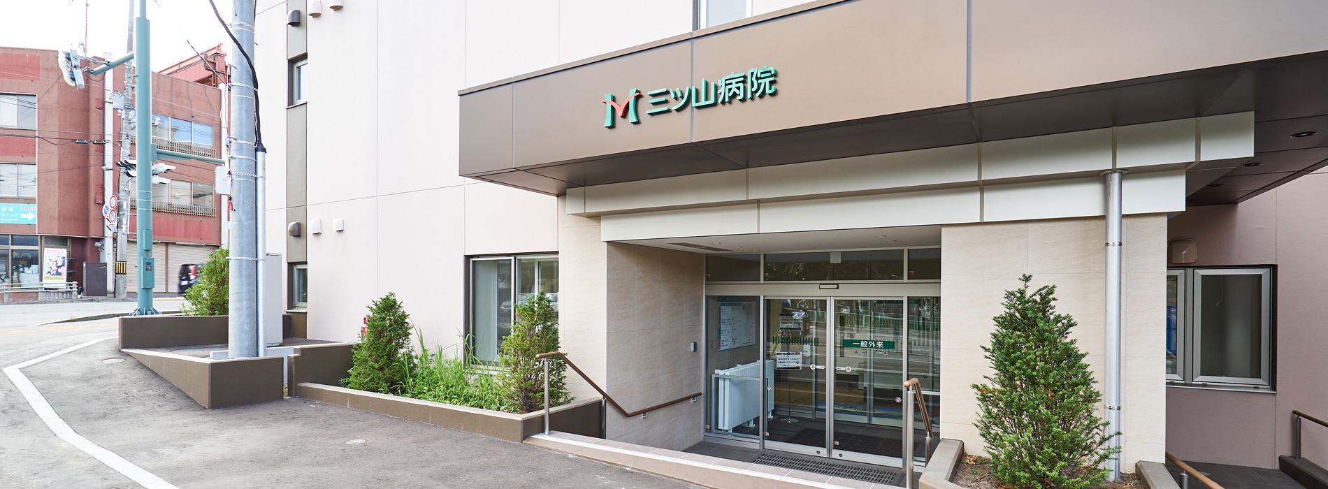 医療施設の建物外観。モダンな玄関エントランスと駐車場スペース。